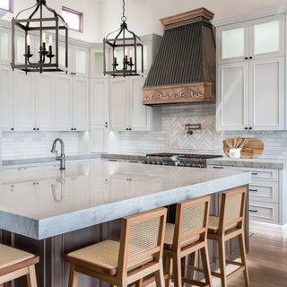 Modern kitchen with marble island, wooden chairs  and decorative range hood