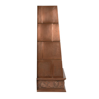 a copper kitchen range hood with a textured, hammered finish and decorative grapevine carvings on the base