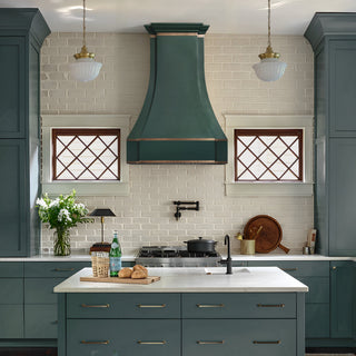 green stainless steel range hood with brass accents in kitchen