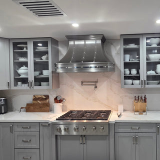 a handmade stainless steel range hood in a modern kitchen