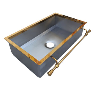 Gray kitchen sink with gold trim and faucet on a white background