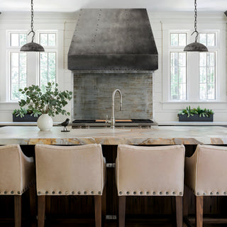 Modern kitchen with island, chairs, and decorative zinc range hood