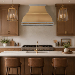 a modern kitchen brushed brass range hood against a light stone backsplash