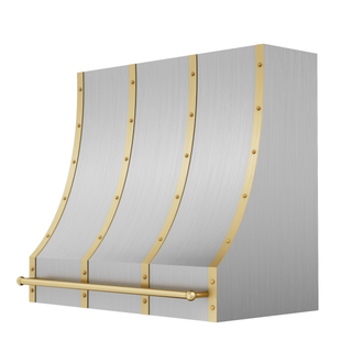  Angled view of a brushed stainless steel range hood: Tapers top-to-bottom with curved edges, features brushed brass straps, round rivets and a pot rail.