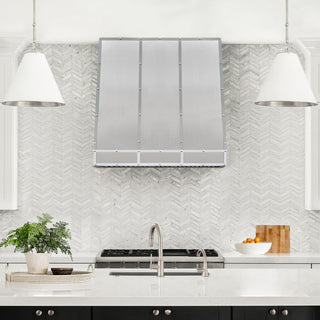 Modern kitchen with a chevron-patterned backsplash, stainless steel appliances, and white countertops.