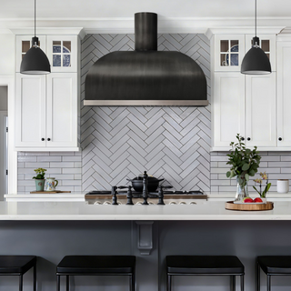 Modern kitchen with white cabinets, and dark grey stainless steel range hood.