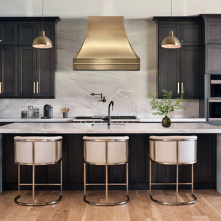 Modern kitchen with dark black cabinets, luxury brushed brass range hood.
