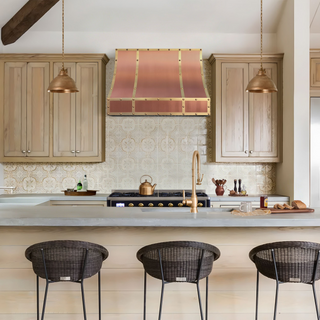 Traditional kitchen with wooden cabinets, antique copper range hood.