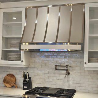 Modern kitchen with stainless steel refrigerator and stove, tiled walls, and modern stainless steel range hood