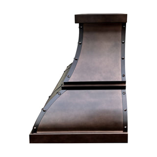Right side view of antique copper range hood highlighting arch-bell profile and strap details.