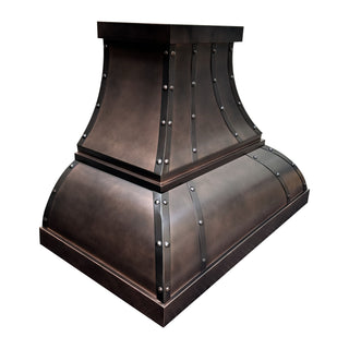 Left front view of handcrafted antique copper kitchen range hood with decorative rivets.